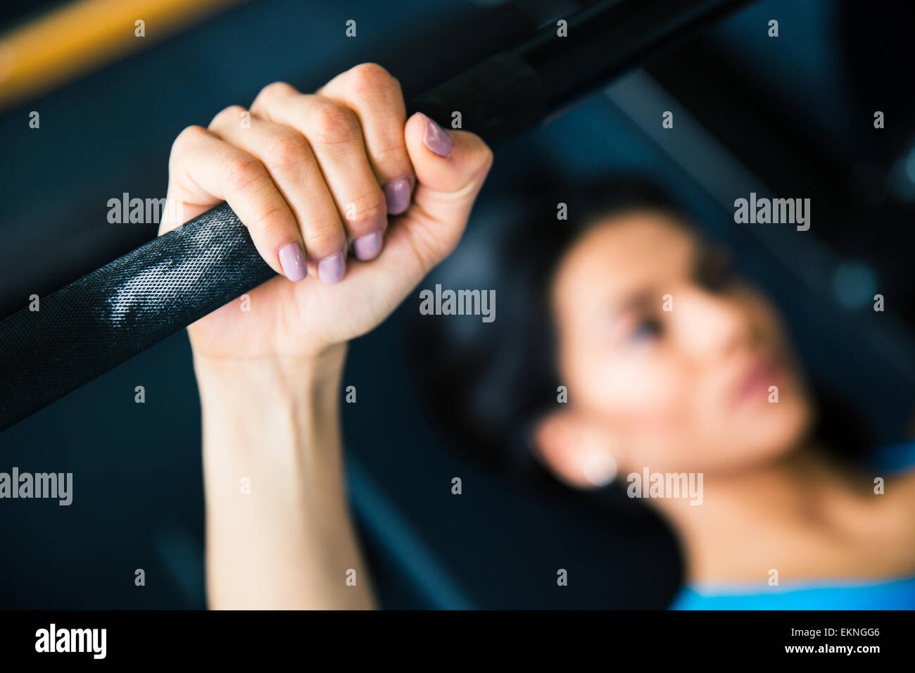 Young fit woman working out with barbell on bench. Focus on barbell ...
