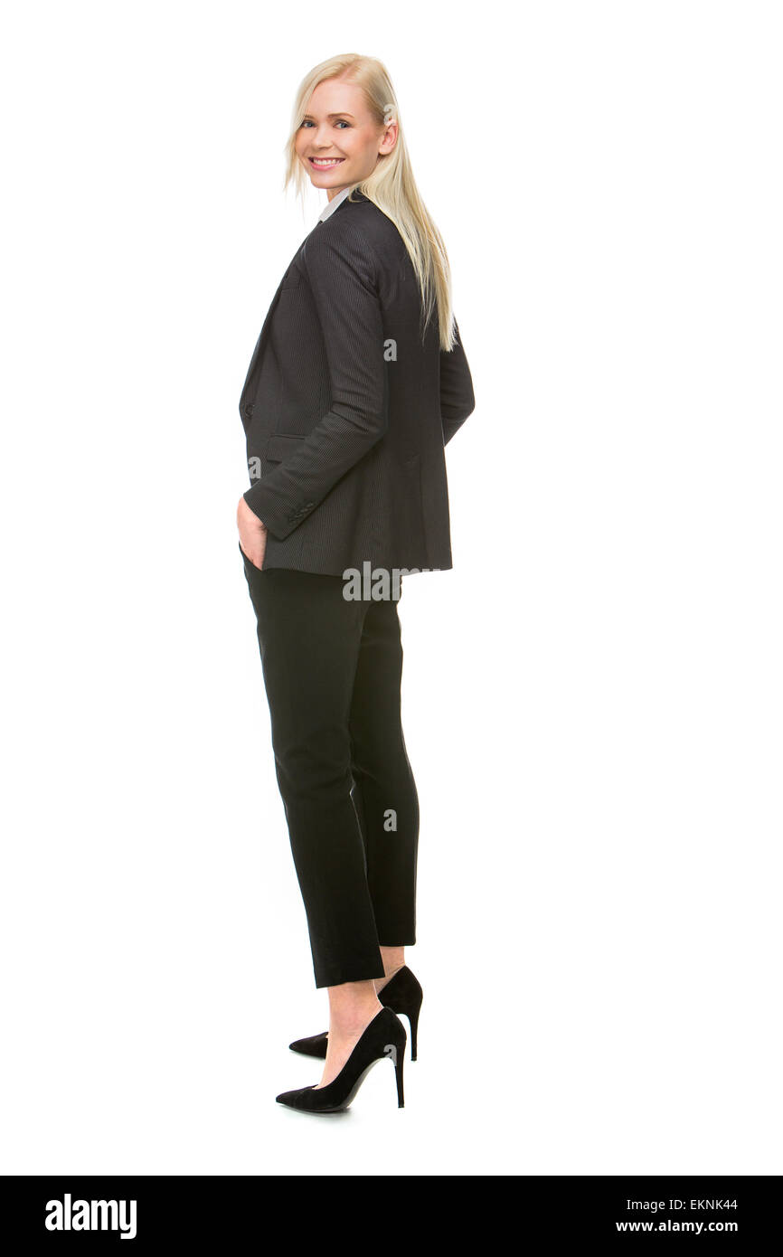 blonde businesswoman turning towards camera, hands in pockets Stock Photo