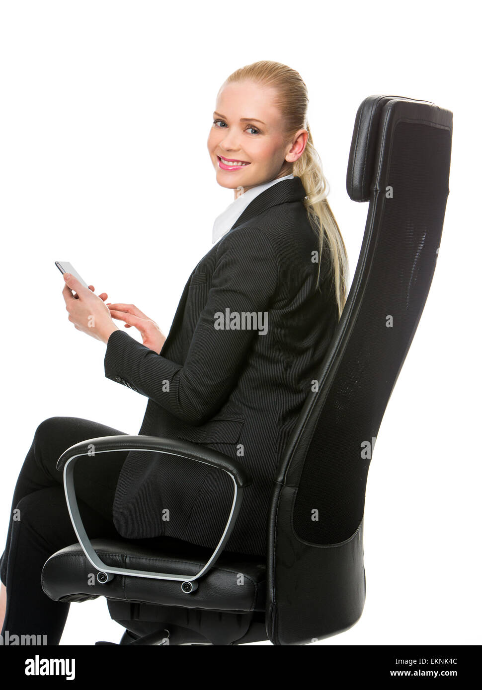 blonde smiling businesswoman seated on a chair working with tablet Stock Photo