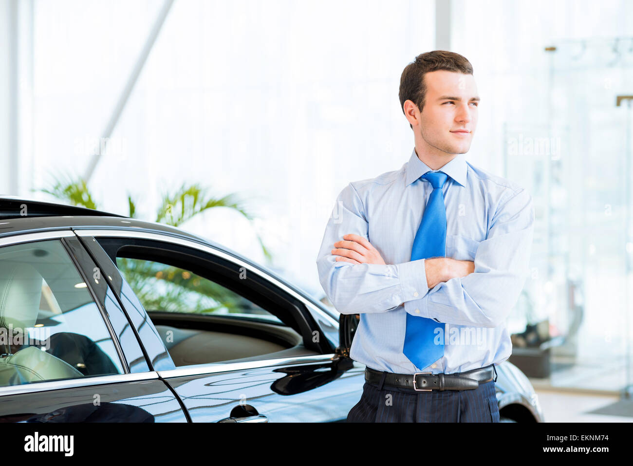 dealer stands near a new car in the showroom Stock Photo Alamy