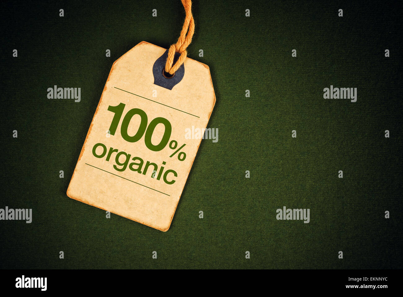 100 Percent Organic Food on Vintage Price Label Tag Label on Green Grunge Textured Background, Top View. Stock Photo