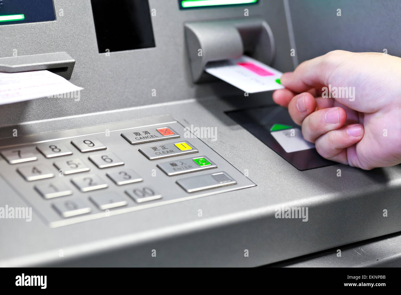 Hand inserting ATM credit card into bank machine to withdraw mon Stock Photo