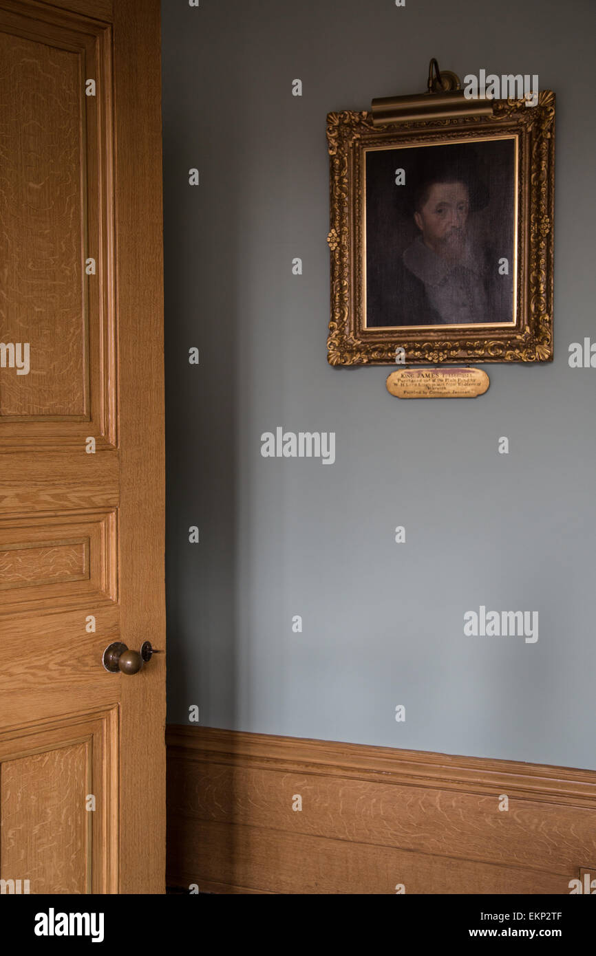An oak panelled door slightly ajar in an english country house, with an old master style painting on the wall Stock Photo