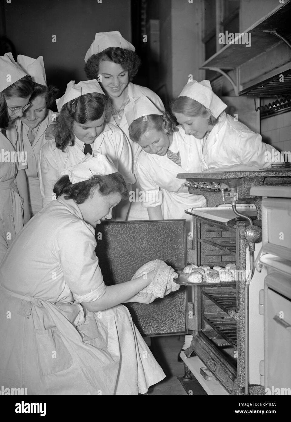 Students of Elizabeth Newcomen School in Southwark, London gather round the oven to see how their cakes have turned out during one of the cookery lessons at the school. The girld were chosen to give a display at County Hall during an exhibition of London Stock Photo