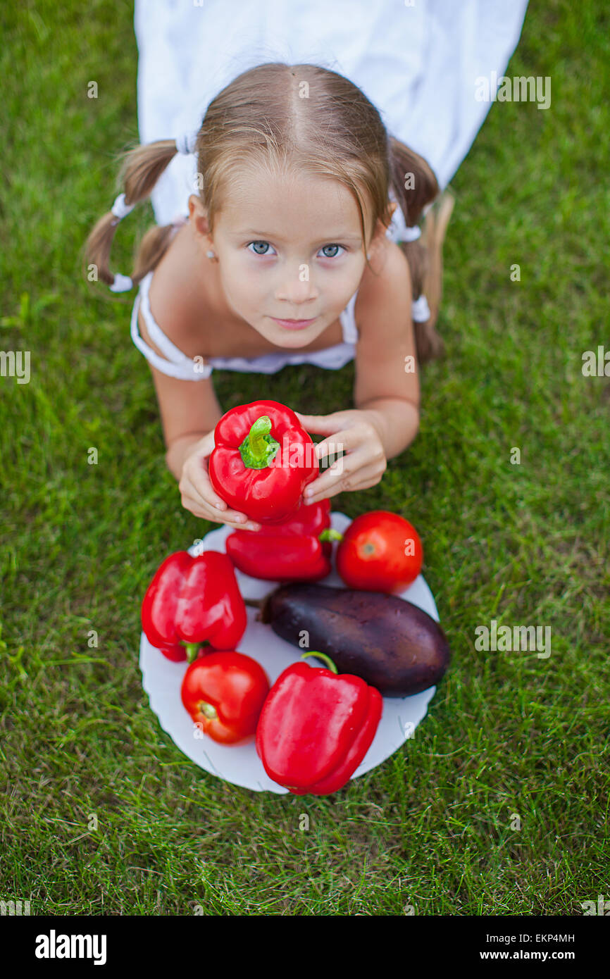 Little girl with pigtails in a garden with a plate of vegetables Stock Photo