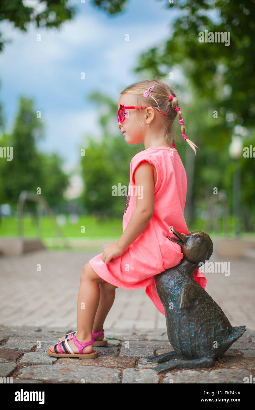 Cute girl astride on a duck figure of iron and having fun Stock Photo