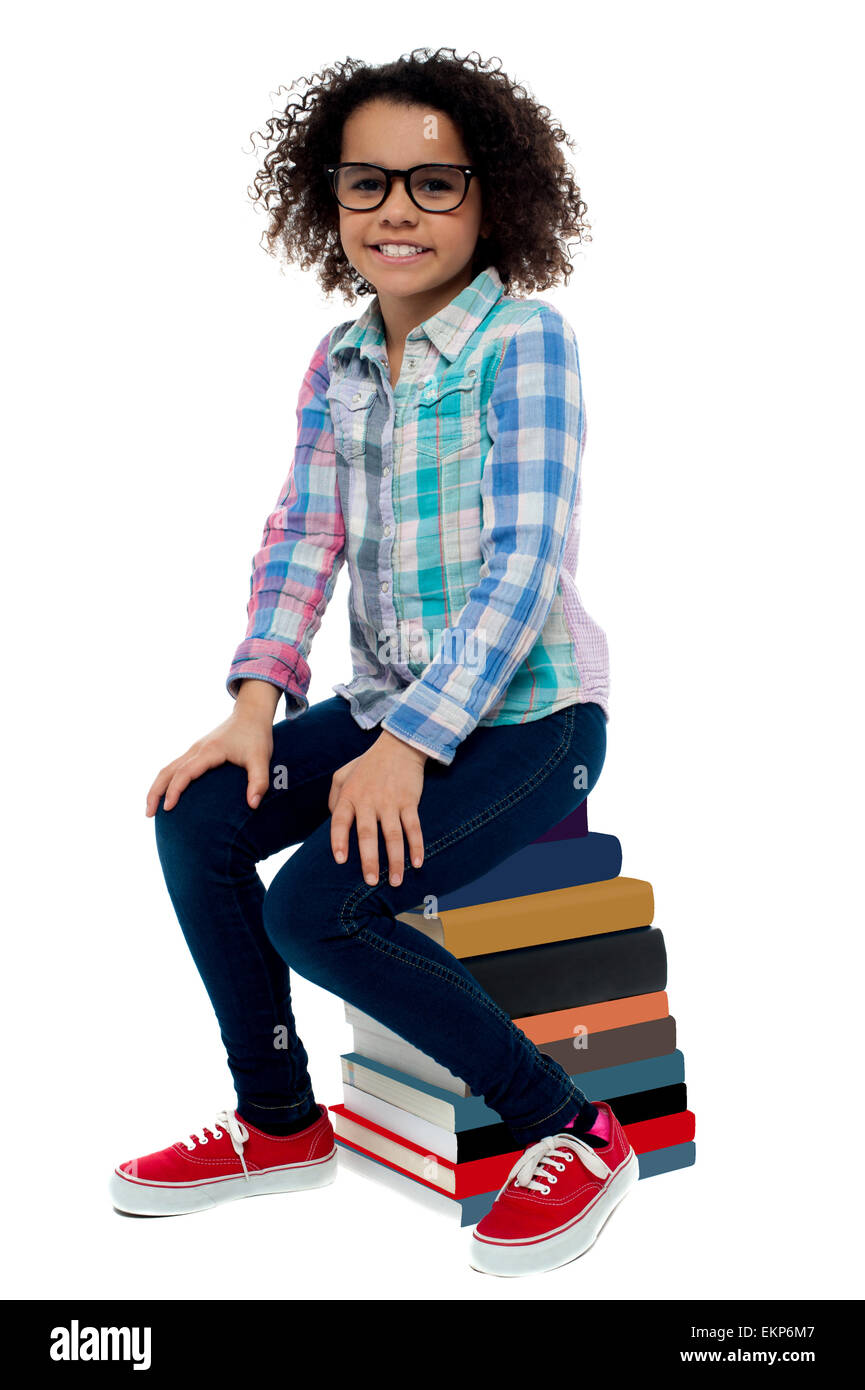 School girl sitting on stack of books Stock Photo - Alamy