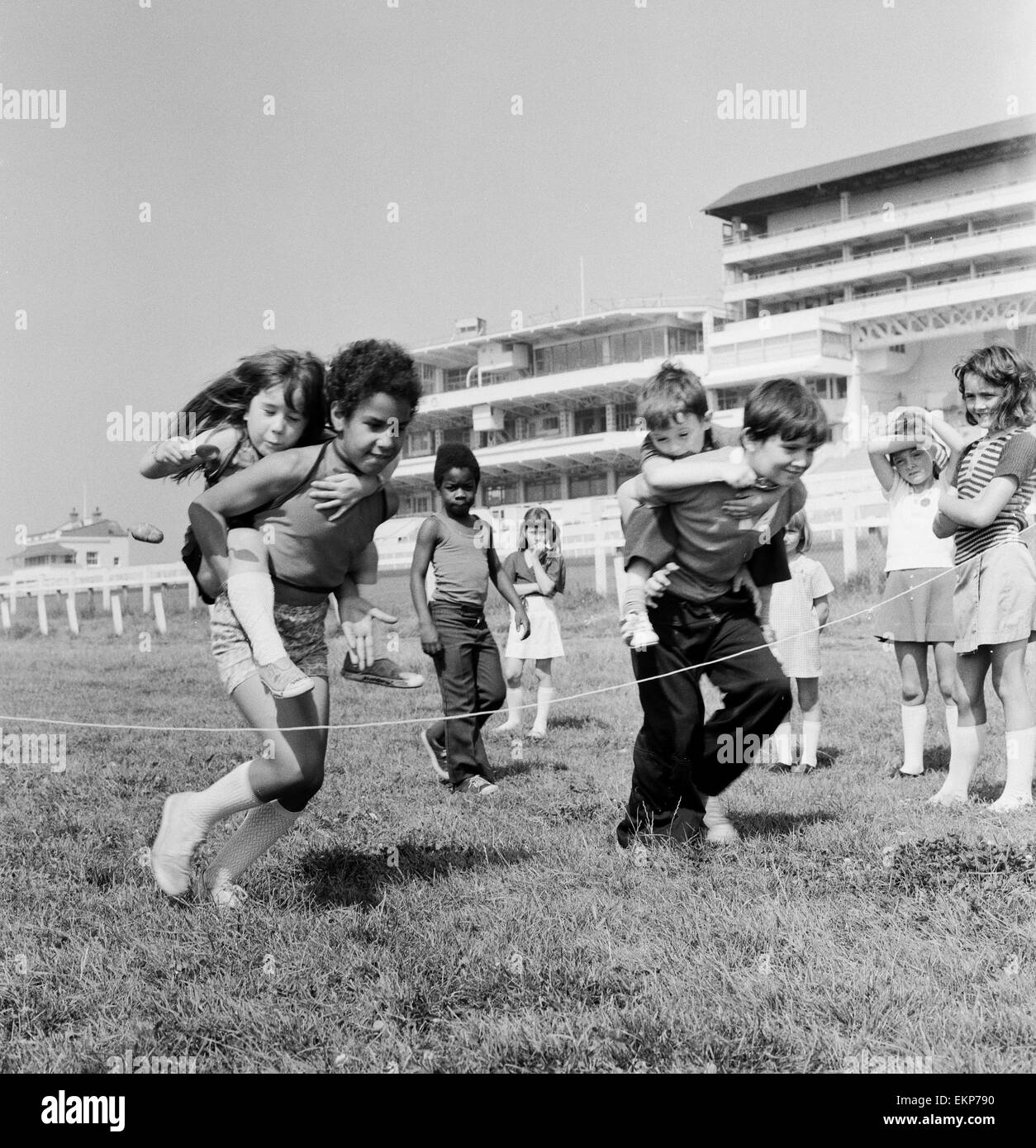 Children carrying their partners on their backs during a horse and jockey style egg and spoon race on the Downs at Epsom where coaches of the children had a holiday away from Peckham. The day out was organised by the Peckham Settlement. 16th August 1973. Stock Photo