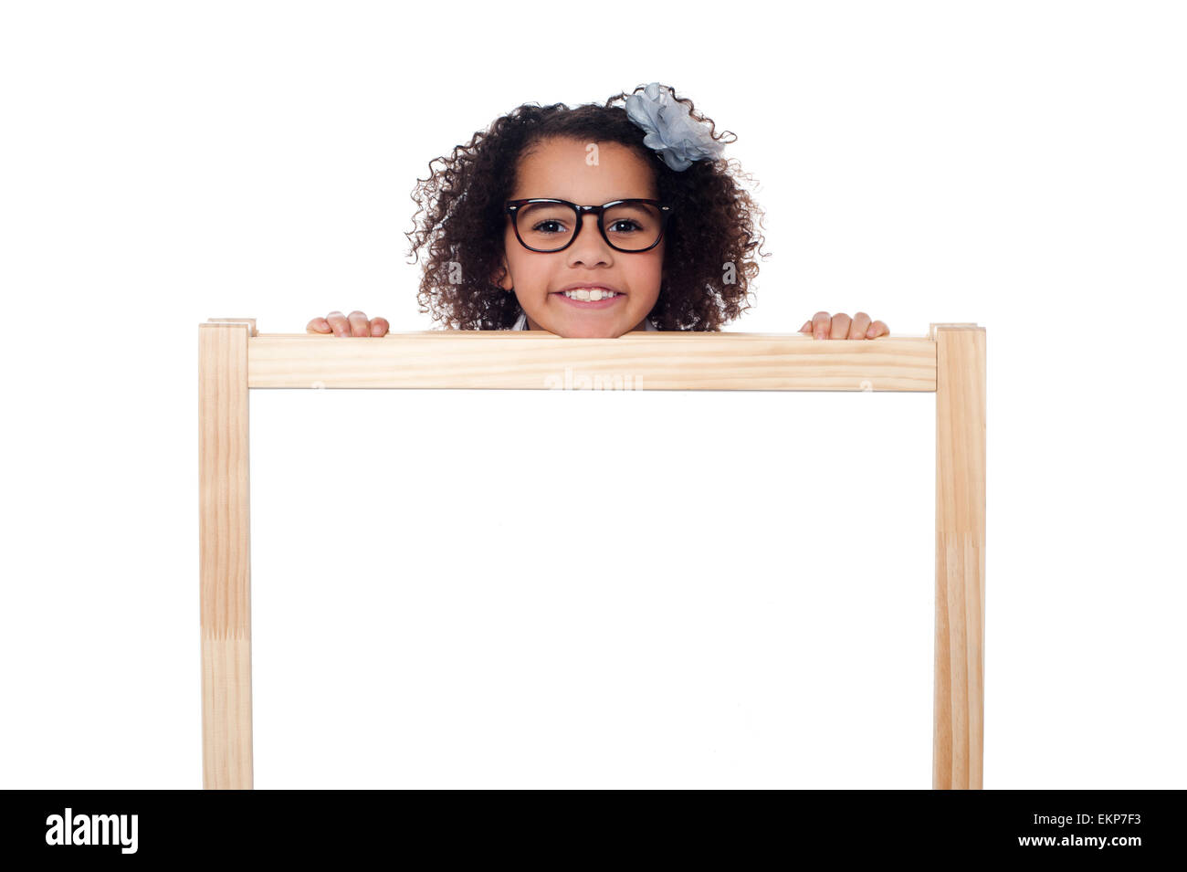Girl peeping from behind white writing board Stock Photo