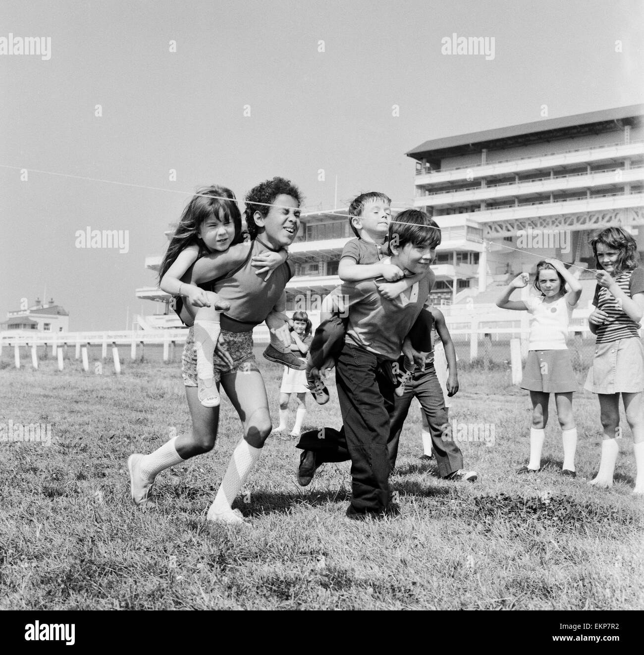 Children carrying their partners on their backs during a horse and jockey style egg and spoon race on the Downs at Epsom where coaches of the children had a holiday away from Peckham. The day out was organised by the Peckham Settlement. Surrey, 16th Augus Stock Photo