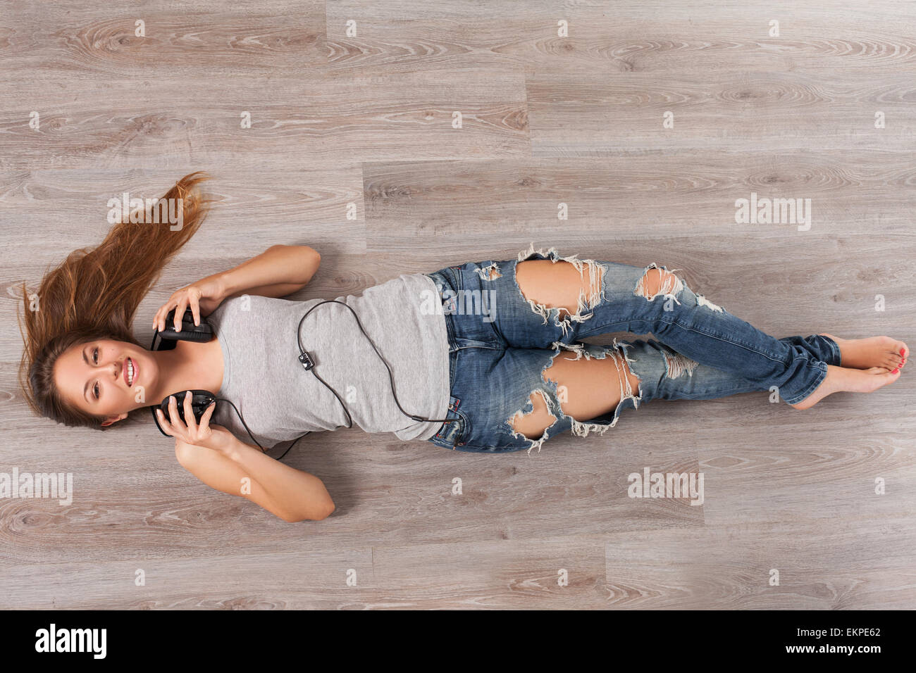Woman lying on a floor with headphones Stock Photo - Alamy