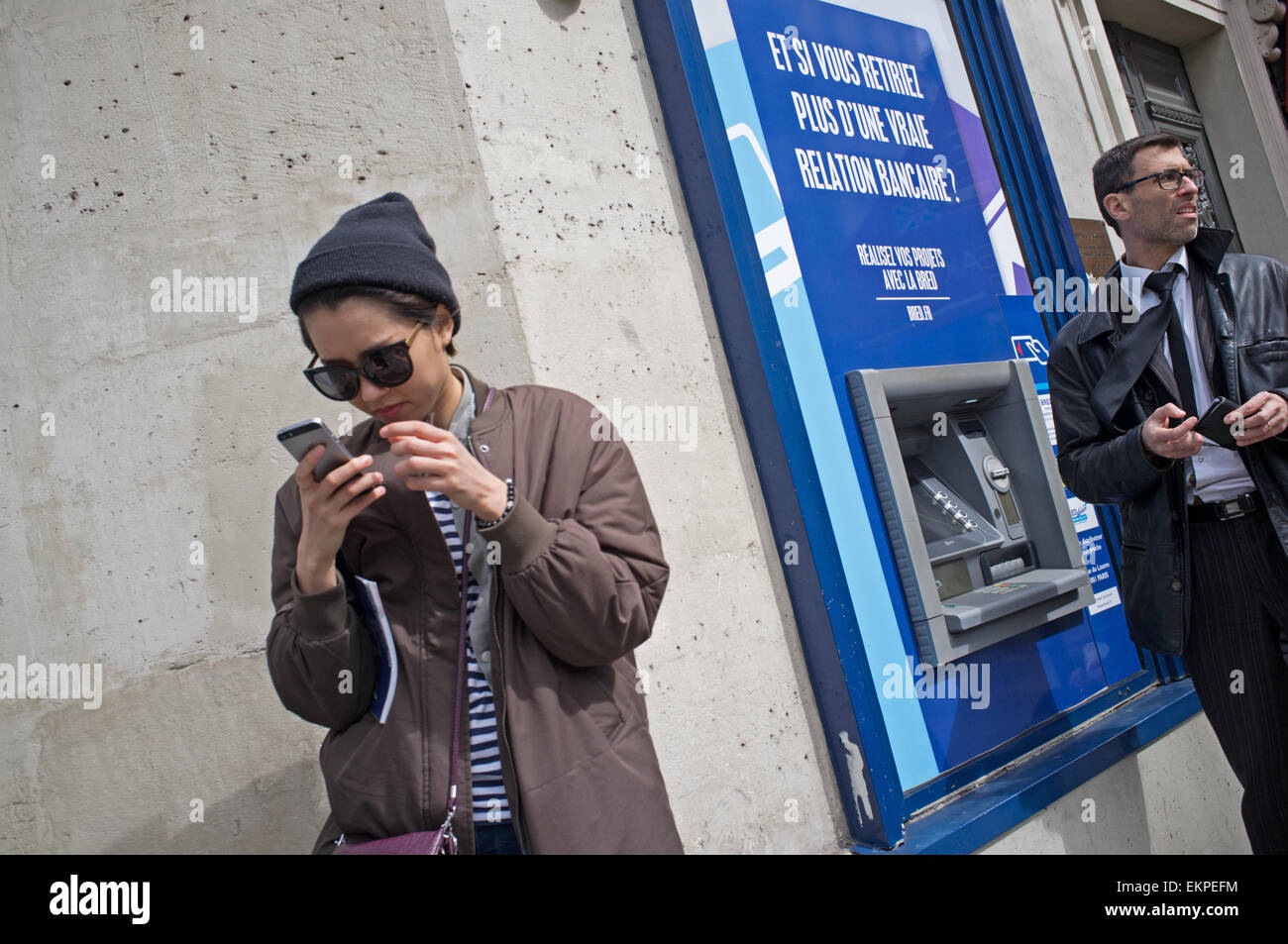 A woman looks at her phone in Paris, France Stock Photo