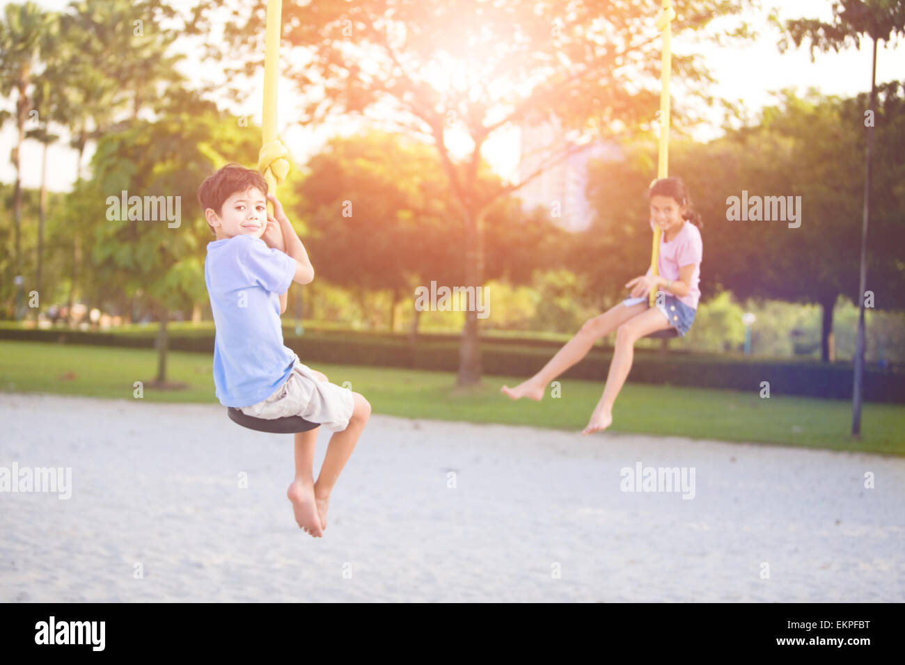 Sister and brother in playground swing outdoors Stock Photo - Alamy