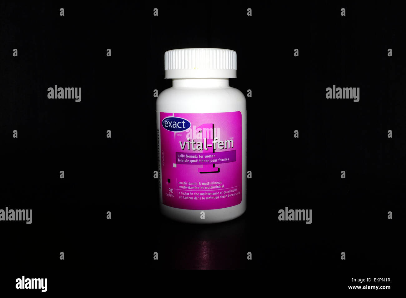 A bottle of female vitamin pills photographed against a black background. Stock Photo