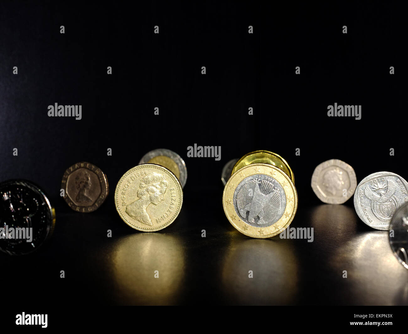 A British Pound and a Euro coin with other coins on a black surface. Stock Photo