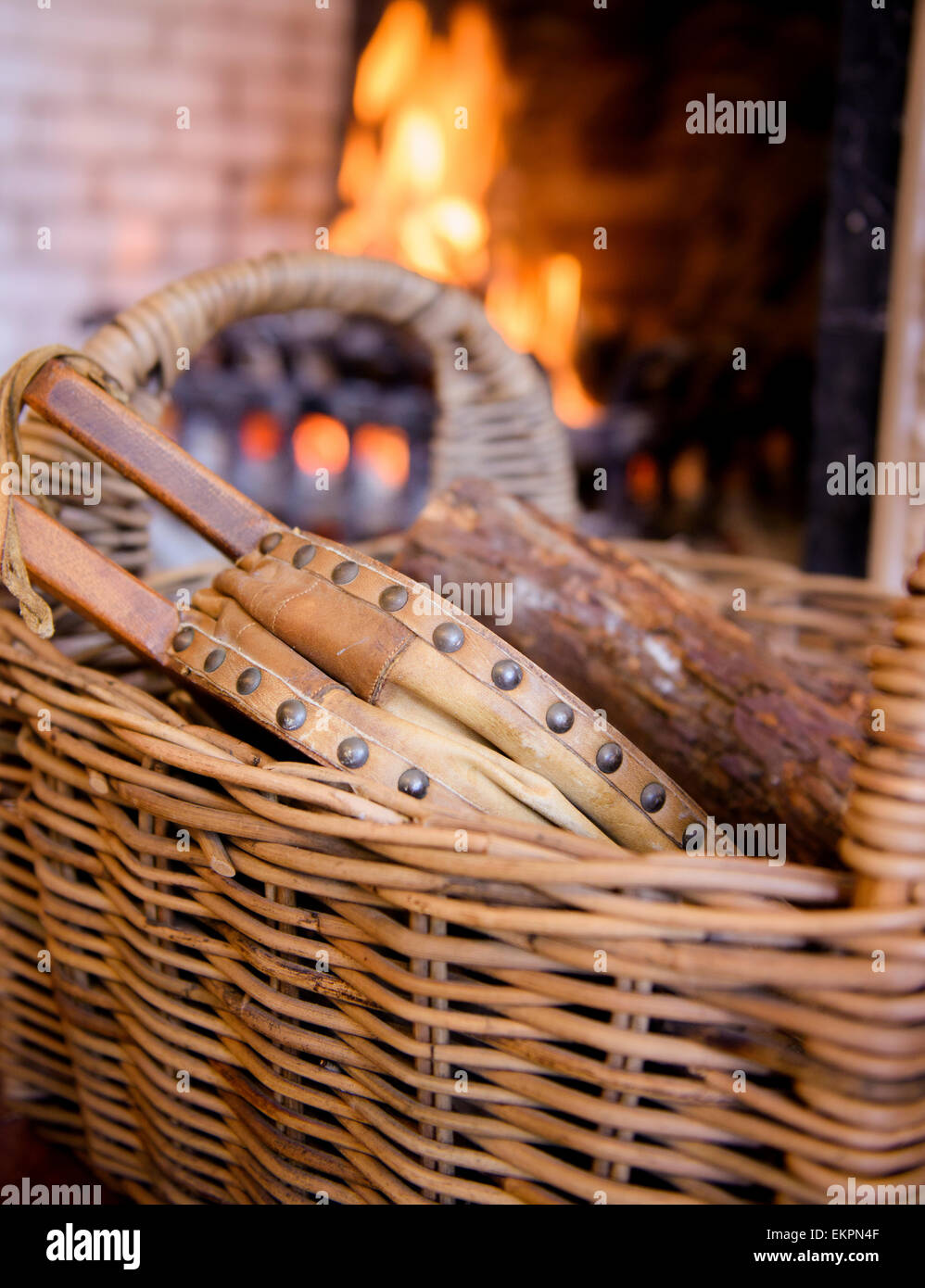 Bellows in a wicker basket in front of an open fire. Stock Photo