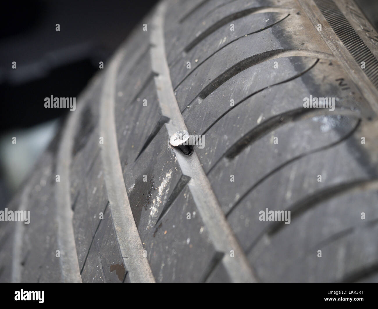 A nearly new car tyre punctured by a deeply embedded screw Stock Photo ...