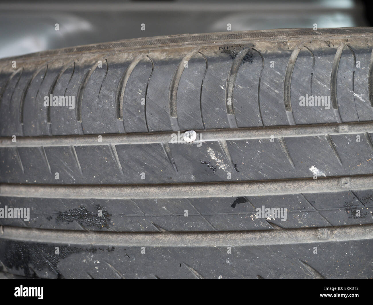 A nearly new car tyre punctured by a deeply embedded screw Stock Photo ...