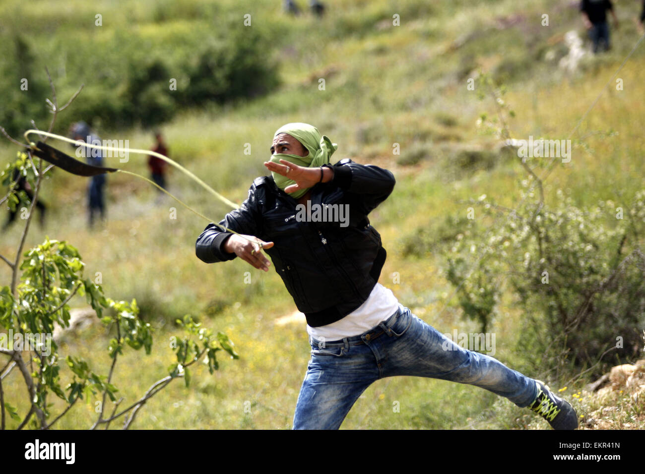 Sinjil, West Bank. 13th Apr, 2015. A Palestinian youth hurls stones towards Israeli security forces during clashes following the funeral of 27-year-old Palestinian Mohammed Jasser Karakra, in Sinjil village. Karakra stabbed two Israeli soldiers in the northern West Bank on April 8, 2015, wounding one seriously before being shot dead. It was the second knife attack in a week targeting Israeli soldiers and the latest in a wave of lone-wolf attacks which have been on the rise since last summer's 50-day war in the Gaza Strip. © Shadi Hatem/APA Images/ZUMA Wire/Alamy Live News Stock Photo