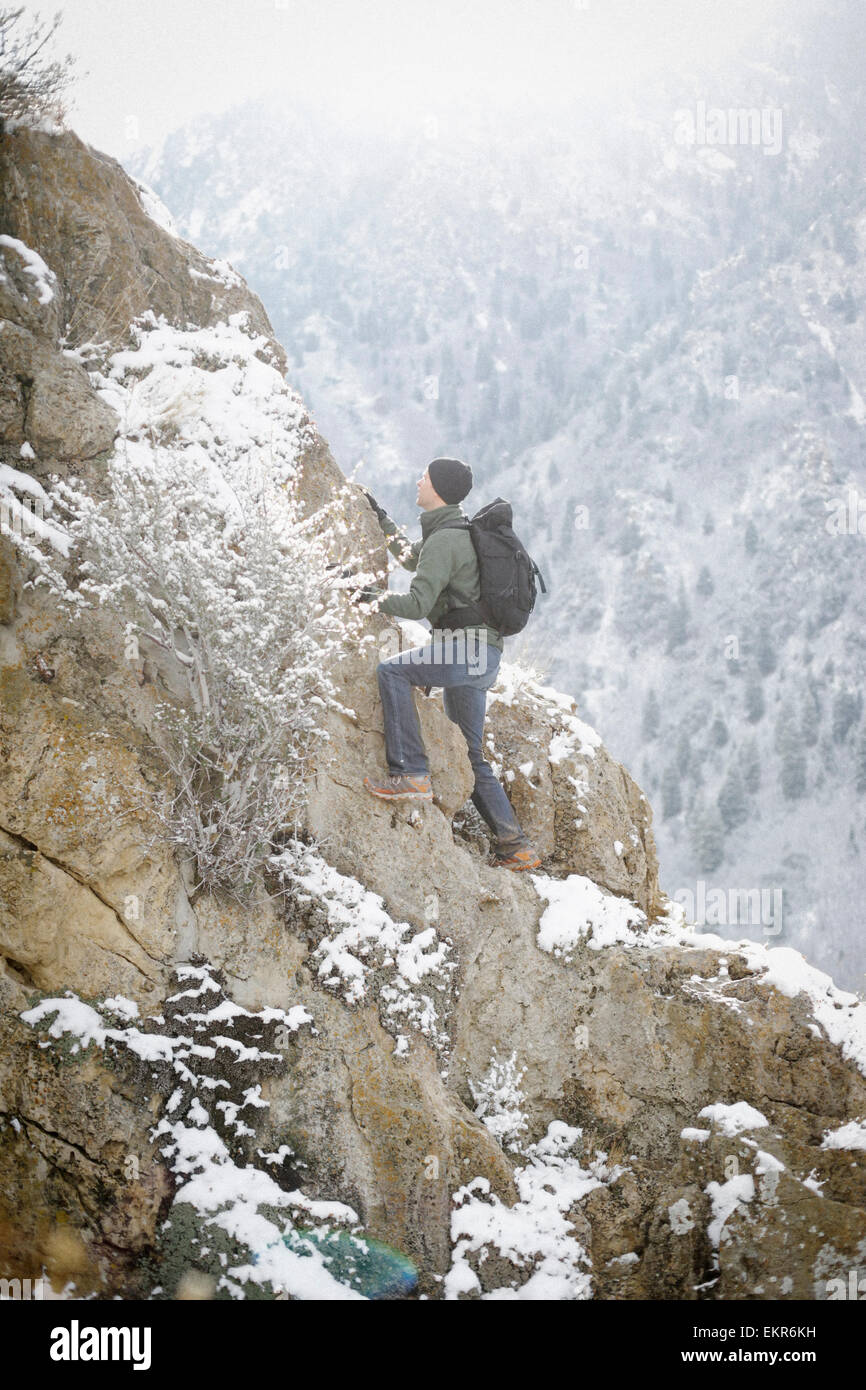 A man hiking in the mountains climbing up a steep rock face. Stock Photo
