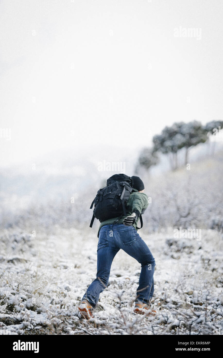 A man running up a slope in the mountains carrying a rucksack. Stock Photo