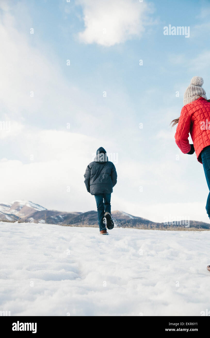 Two children, brother and sister running across the snow Stock Photo ...