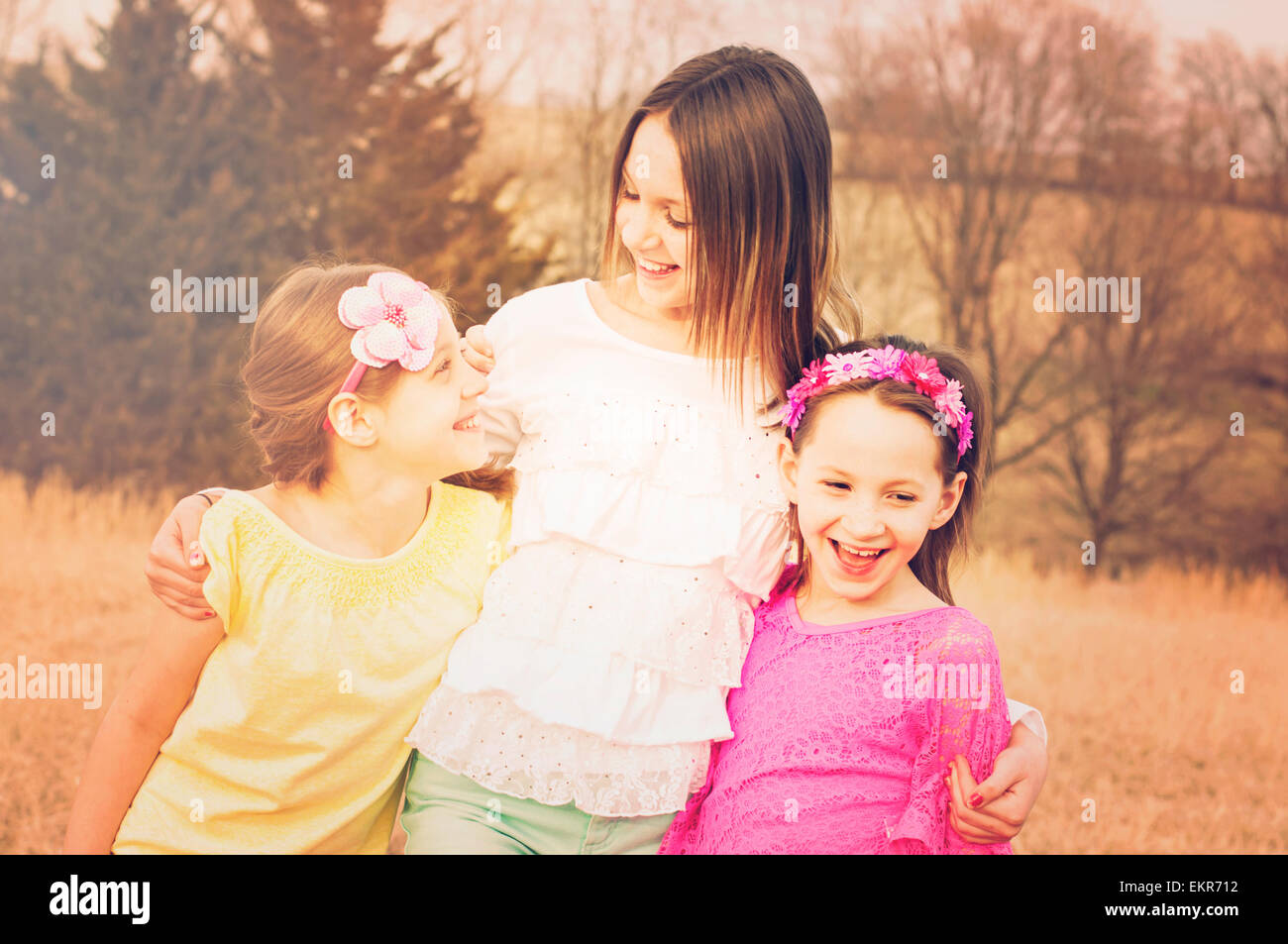 Three happy sisters together  in a meadow Stock Photo