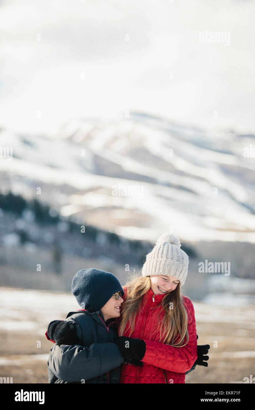 A brother and sister hugging and laughing together outdoors. Stock Photo