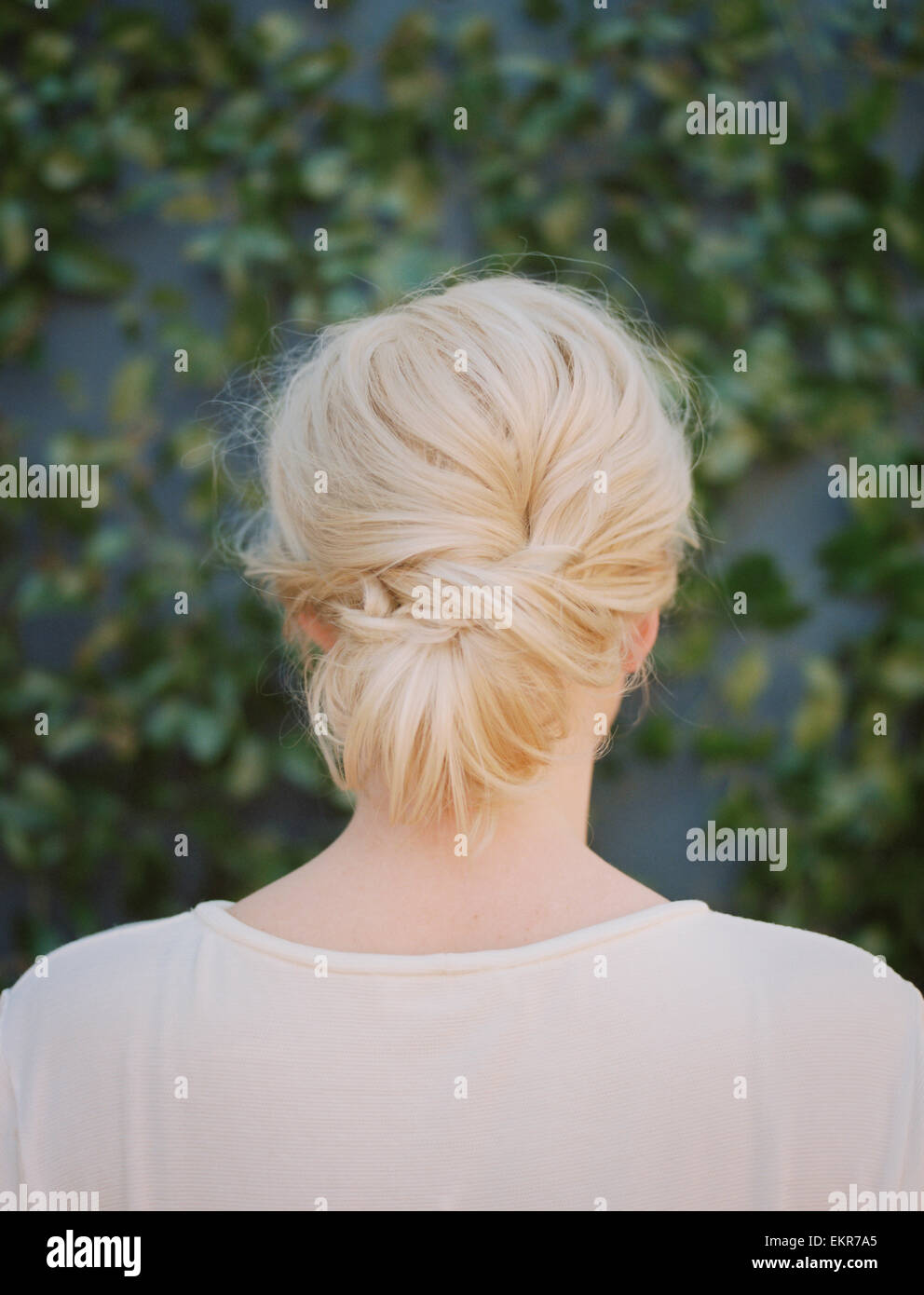 A woman with blonde hair arranged in a knot at the nape of her neck