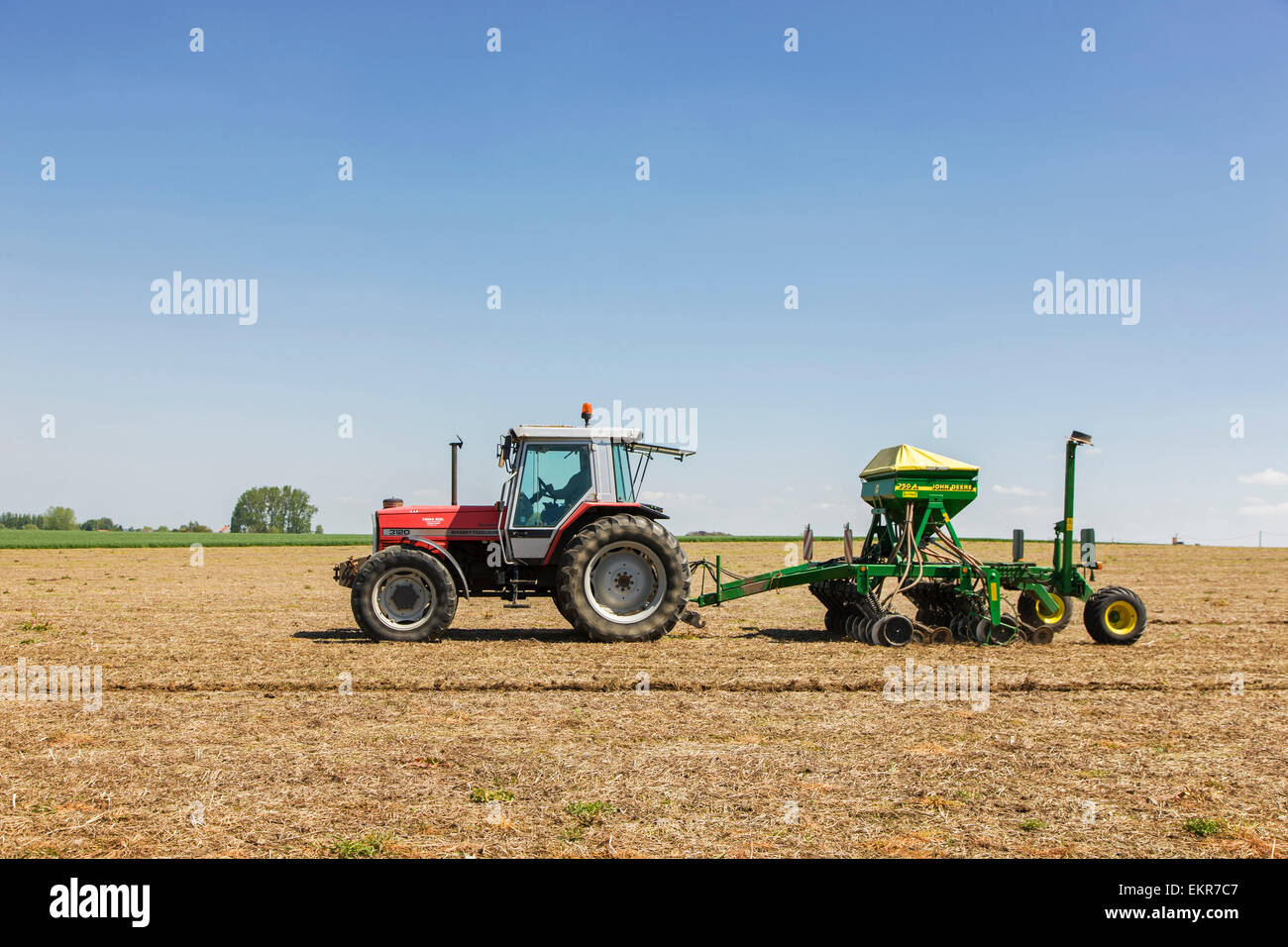 Tractor pulling John Deere 750A no-till seed drill working on farmland Stock Photo