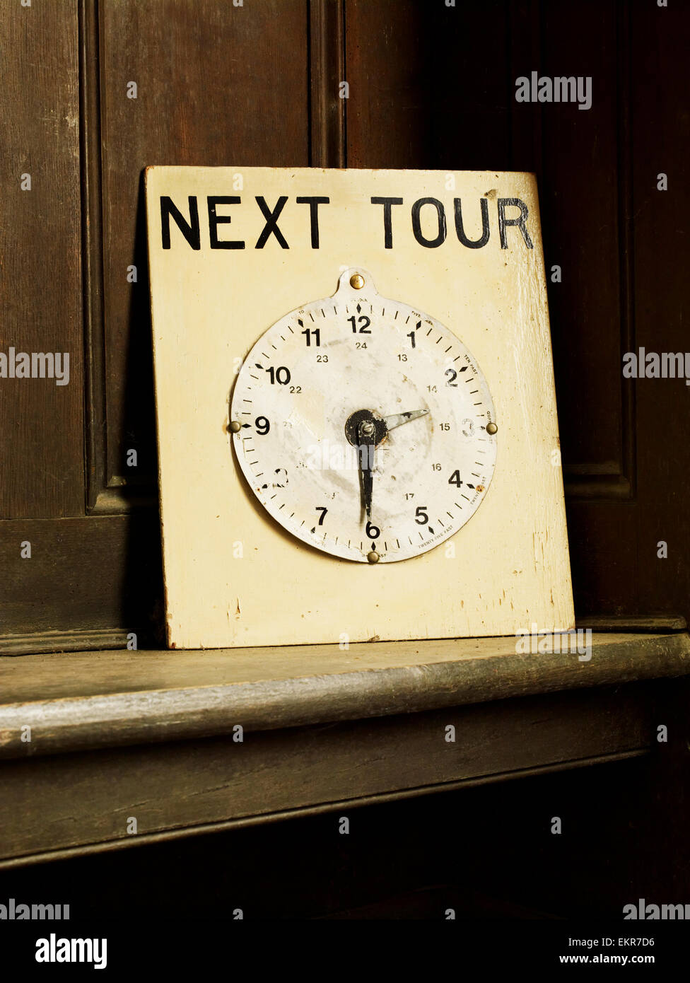 A clock face on a board with hands set to the time 2.30pm indicating the next guided tour of a house. Stock Photo