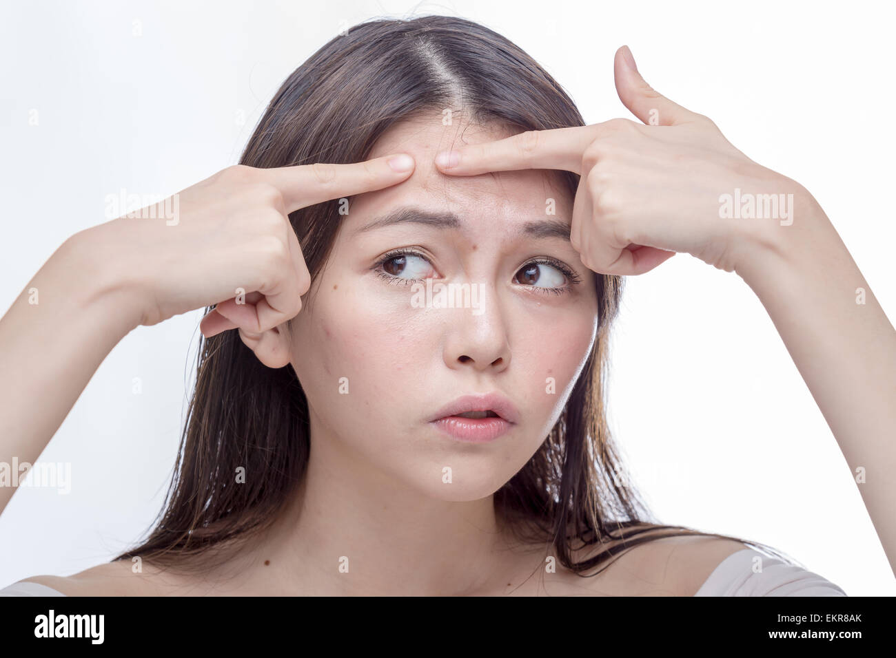 Chinese woman squeezing a spot on her forehead Stock Photo