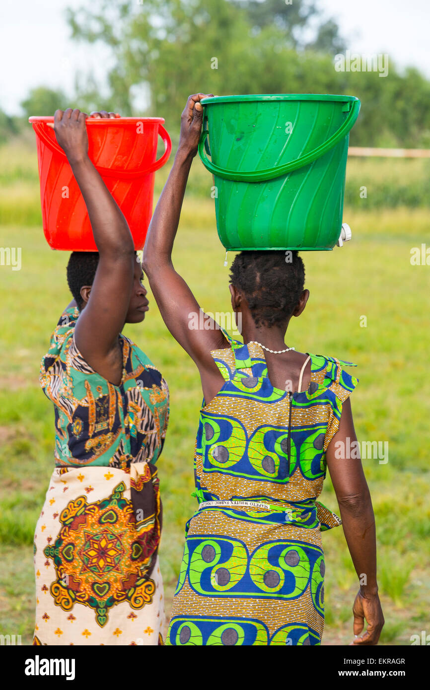 In mid January 2015, a three day period of excessive rain brought unprecedneted floods to the small poor African country of Malawi. It displaced nearly quarter of a million people, devastated 64,000 hectares of alnd, and killed several hundred people. This shot shows a displaced women carrying water in the refugee camp of Chiteskesa refugee camp, near Mulanje. Stock Photo