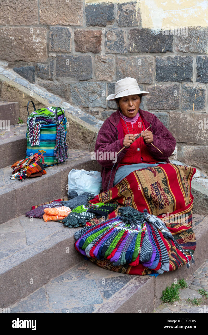 Peru, Cusco.  Quechua Woman Knitting while Offering Items for Sale. Stock Photo