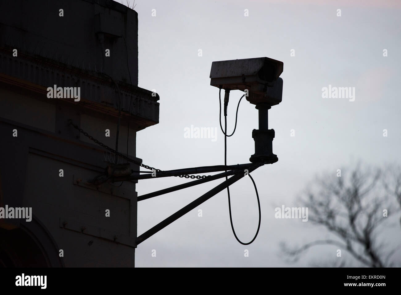 A CCTV security camera silhouetted in a city centre. Stock Photo
