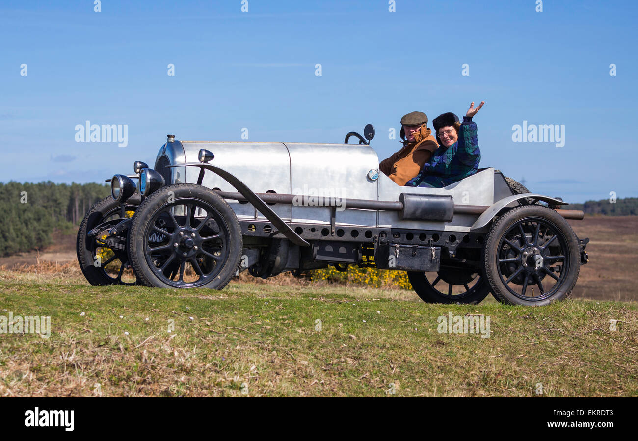 A vintage car competing in the Daffodil Run in the New Forest on a sunny day. The passenger is waving and smiling. Stock Photo