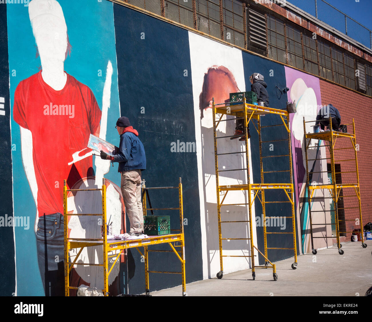 Sign painters paint an advertisement on the side of building in the