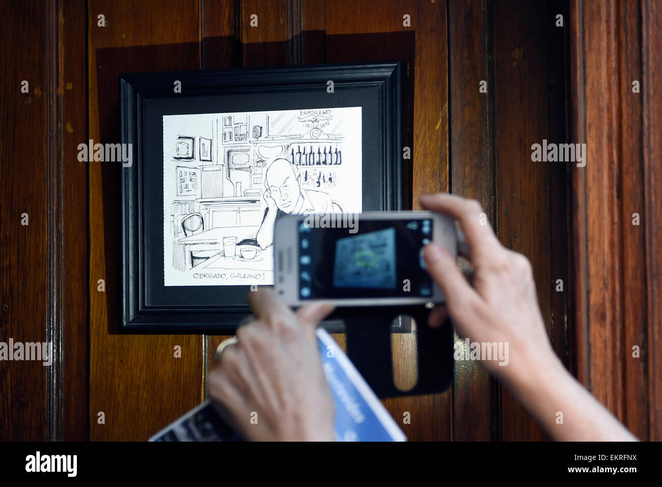 Montevideo, Uruguay. 13th Apr, 2015. A tourist takes a picture of a cartoon of the Uruguayan writer, Eduardo Galeano, in the 'Cafe Brasilero', which he used to visit, in the Ciudad Vieja, in Montevideo, capital of Uruguay, on April 13, 2015. Uruguayan writer Eduardo Galeano, author of 'Open Veins of Latin America', died on Monday in Montevideo at 74 years old. © Nicolas Celaya/Xinhua/Alamy Live News Stock Photo