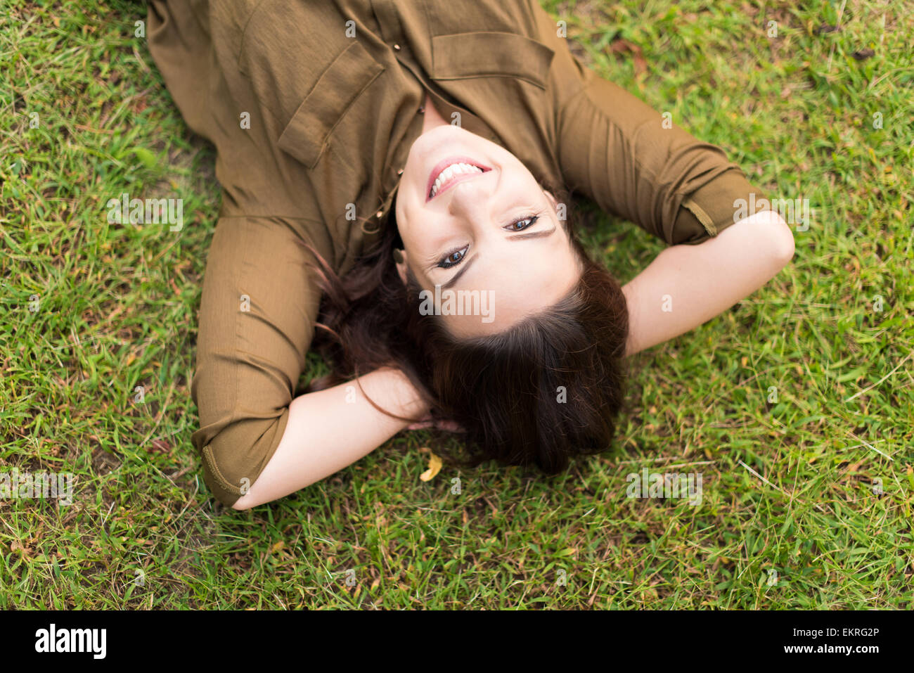 Smiling woman lying and relaxing in grass Stock Photo - Alamy