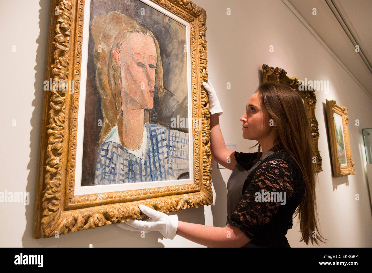 London, UK. 13 April 2015. A Christie's employee handles the Amedeo Modigliani painting Portrait de Béatrice Hastings, 1916 (estimate $7-10million) from the Collection of John C. Whitehead. Christie's showcases a selection of almost fifty works from the spring sales in May in New York of Impressionist, Modern, Post-War And Contemporary Art. Most works will be on view to the public until 15 April at Christie’s King Street, London. Photo: ukartpics/Alamy Live News Stock Photo