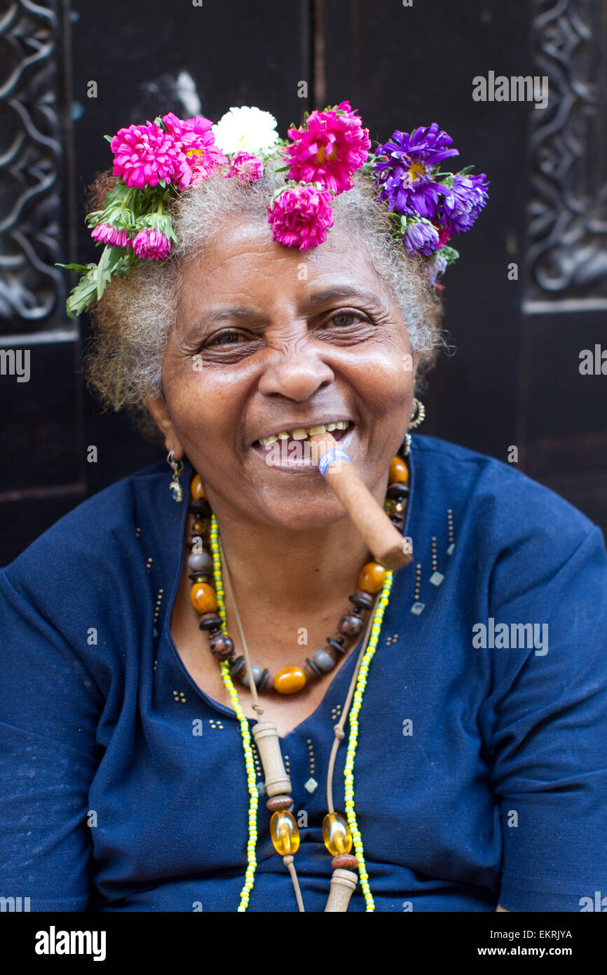 An elderly woman with flowers in her hair smoking a cigar in Havana,Cuba Stock Photo