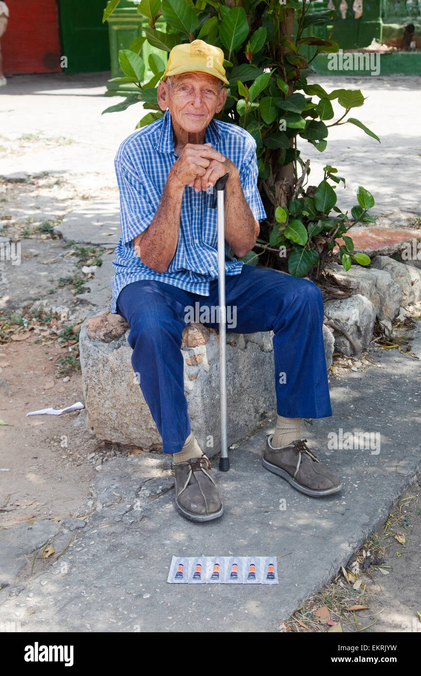 Elderly man in Havana sitting down with stick selling six tubes of superglue Stock Photo