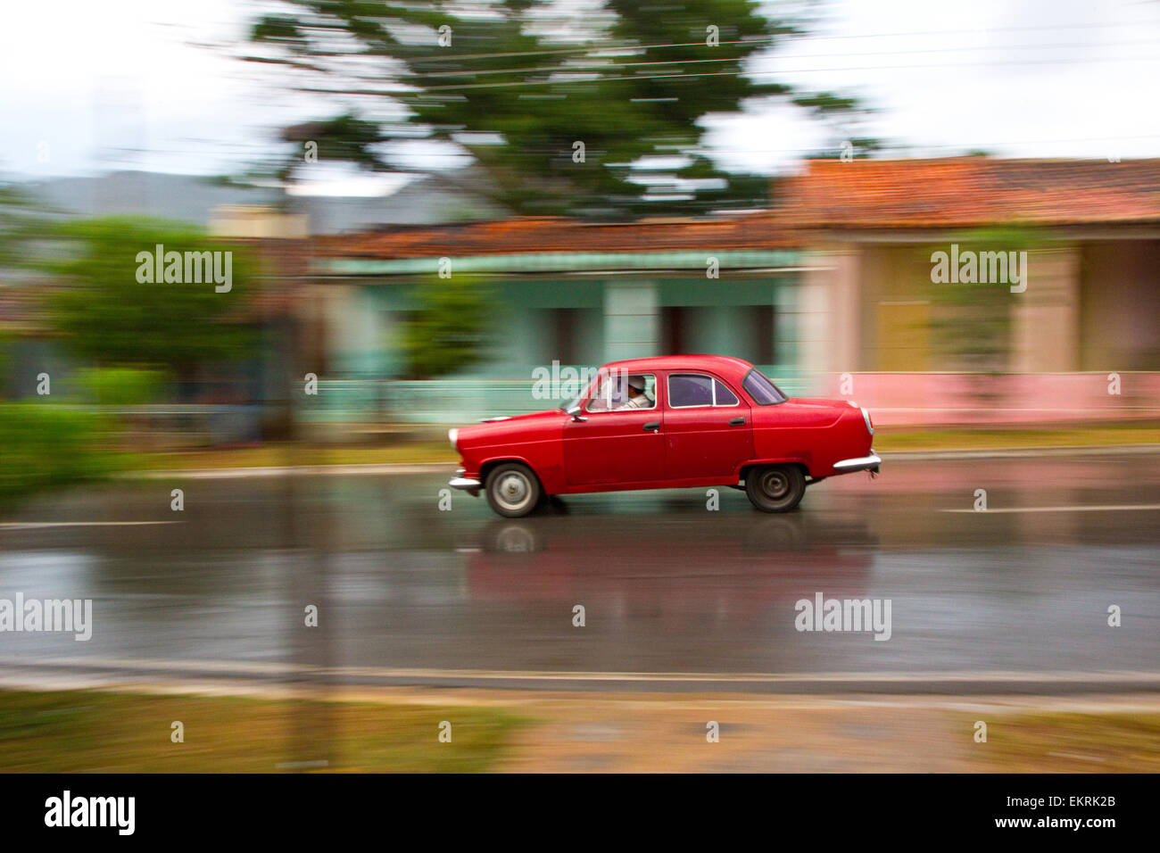 A red car zooms down the main street in Vinales,Cuba Stock Photo