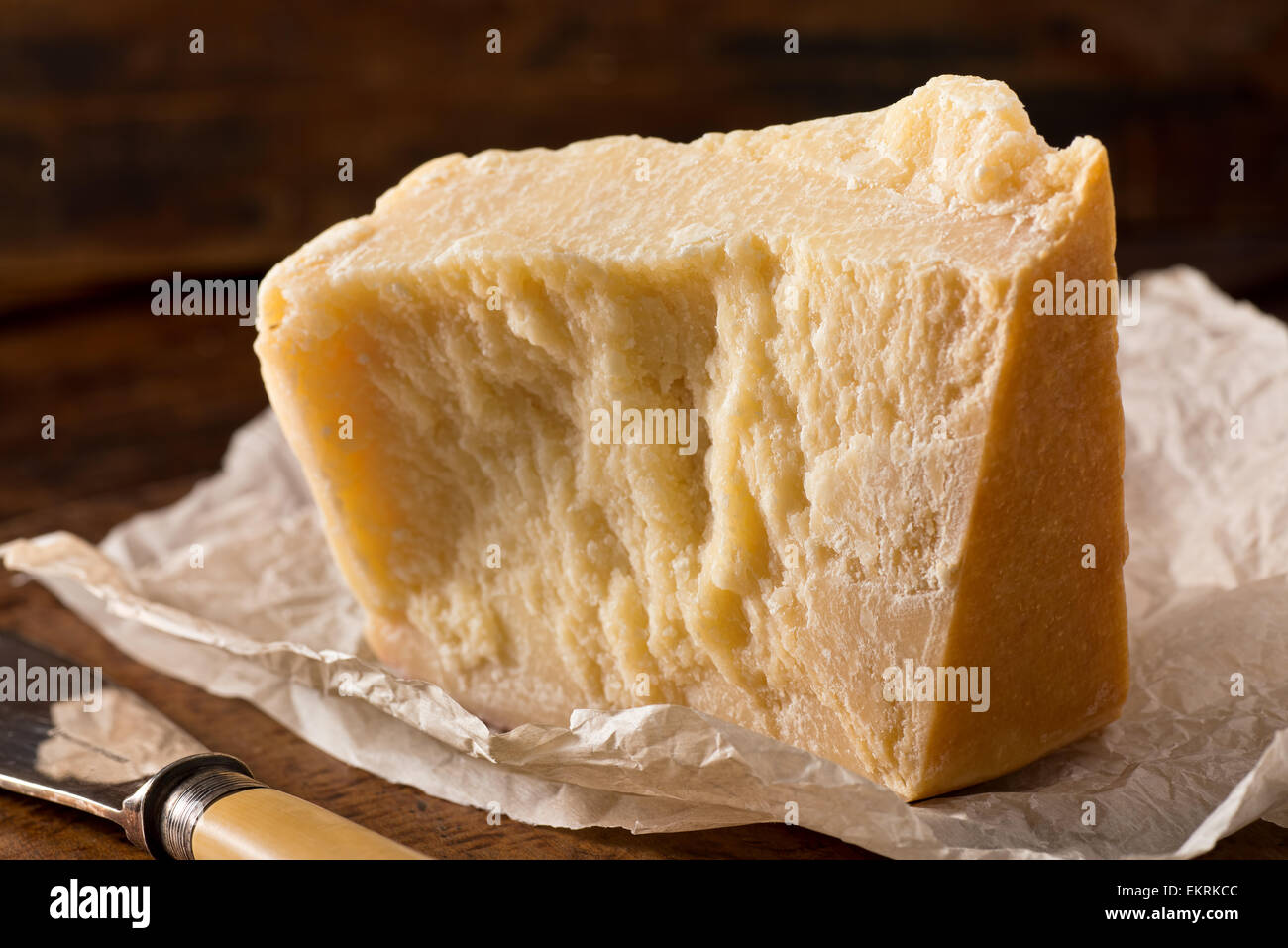 An aged authentic parmigiano reggiano parmesan cheese with wrapper and cheese knife. Stock Photo