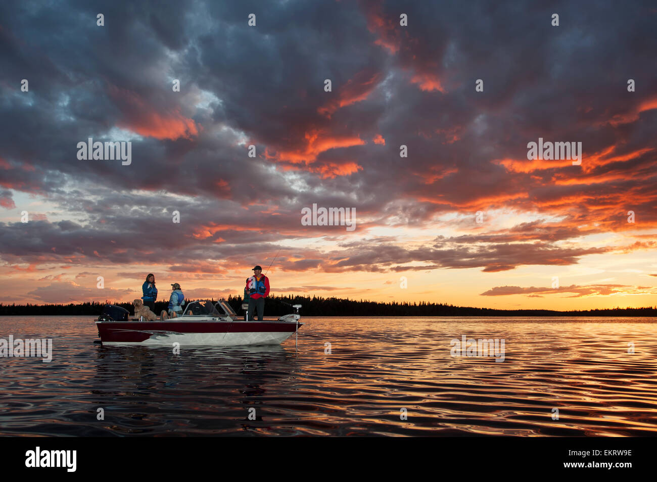A family fishing from their motorboat on a calm lake at sunset in ...