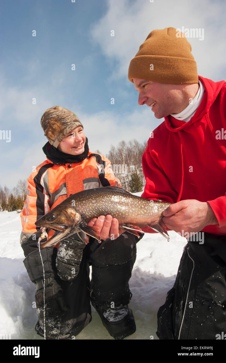 Father and son with a large winter brook trout caught while ice fishing