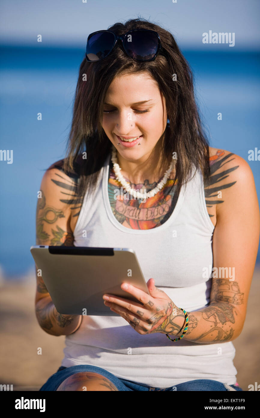 Young Woman With Tattoos Using A Tablet While Sitting By Lake Simcoe; Ontario Canada Stock Photo