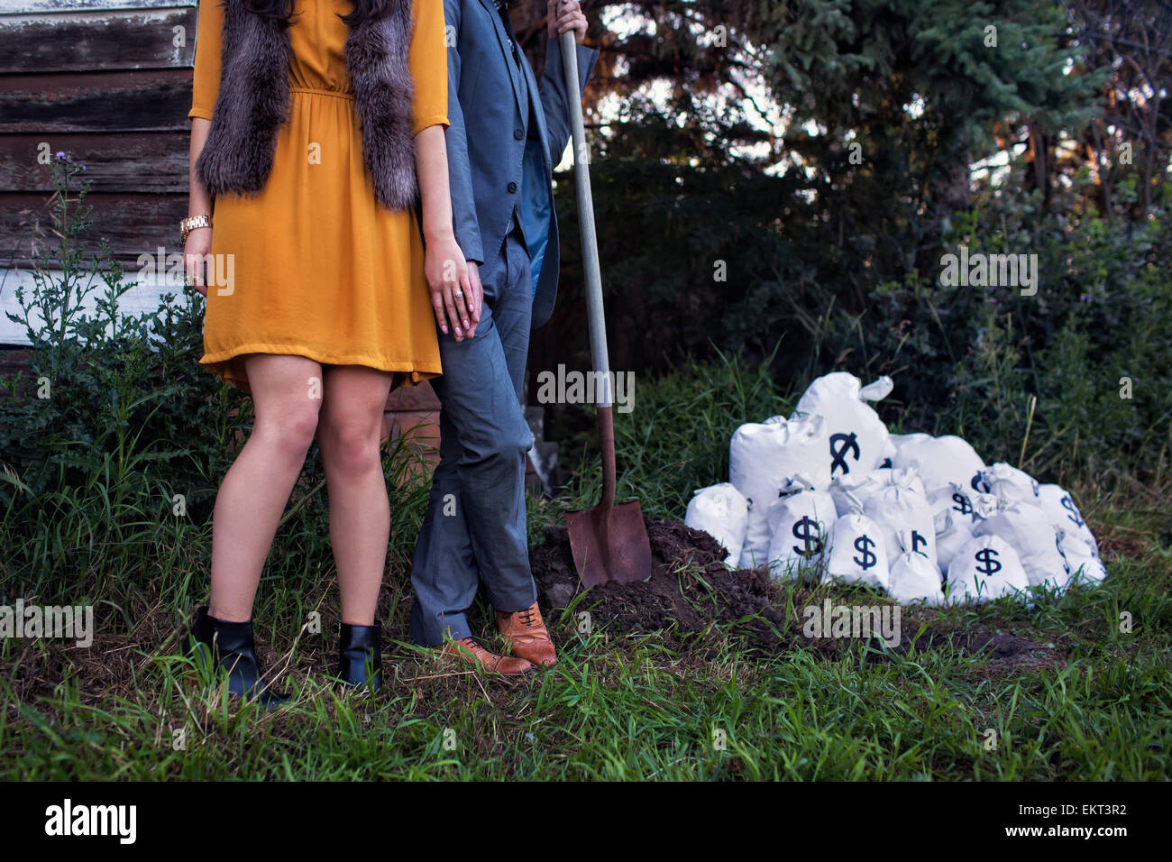 A man and woman dressed in vintage clothing holding a shovel to bury