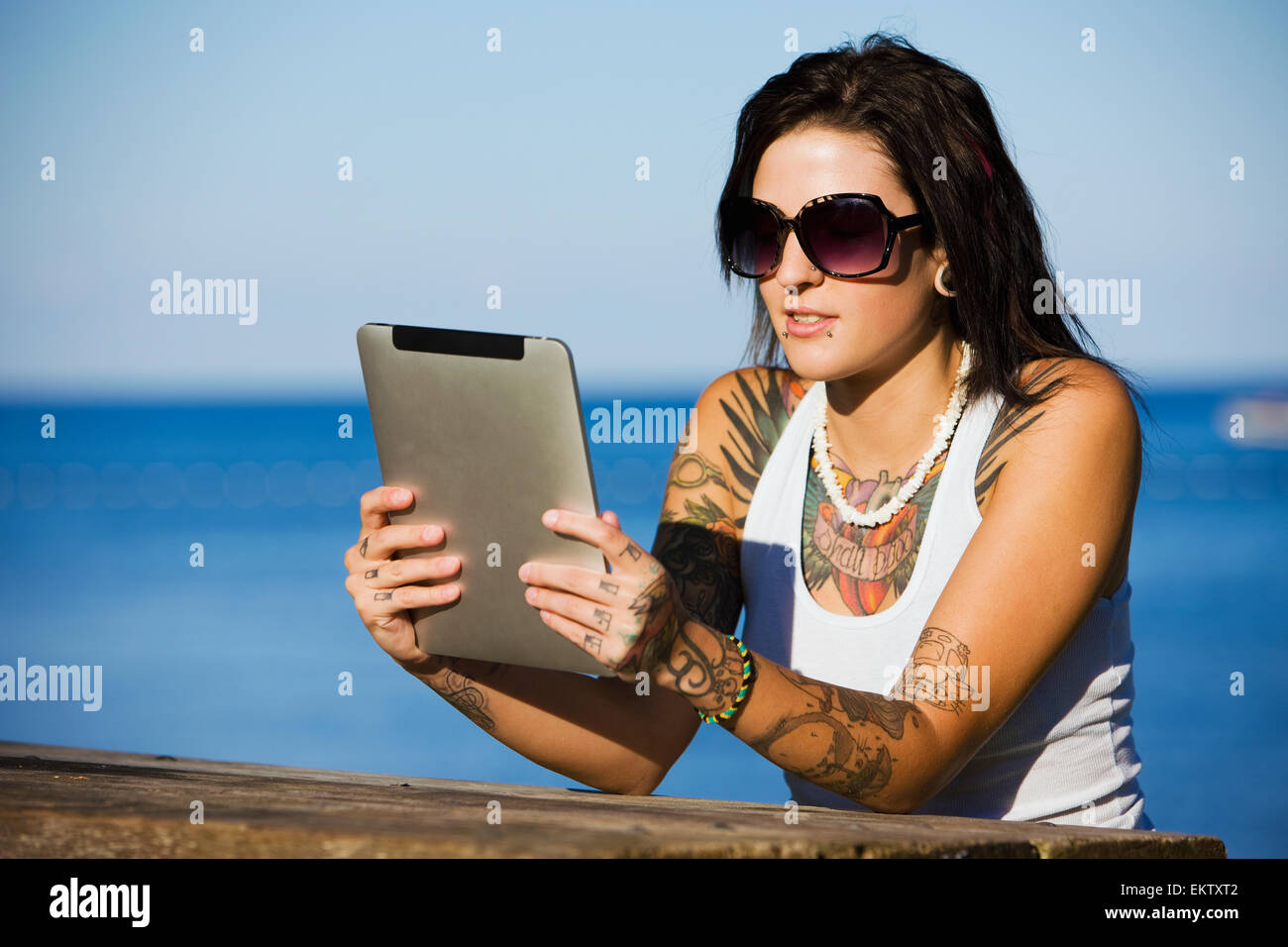 Young woman sitting at a picnic table by a lake using a tablet;Ontario canada Stock Photo