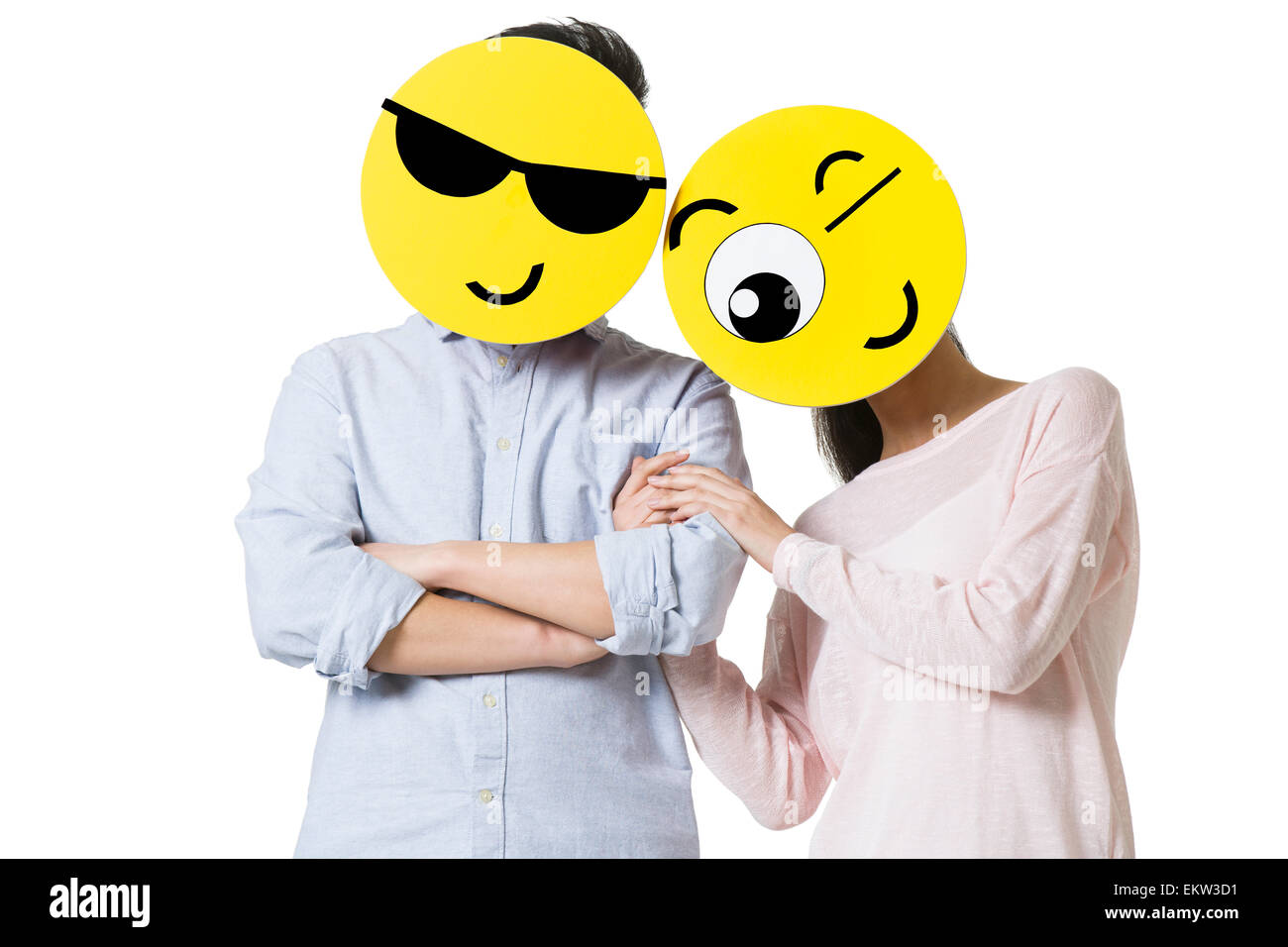 Young couple with cartoon emoticon faces in front of their faces Stock Photo